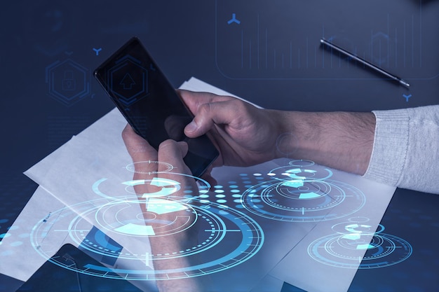 Programador segurando nas mãos um telefone inteligente e testando um aplicativo inovador para fornecer um serviço completamente novo Close up shot Gráficos técnicos de holograma Conceito de equipe de desenvolvimento